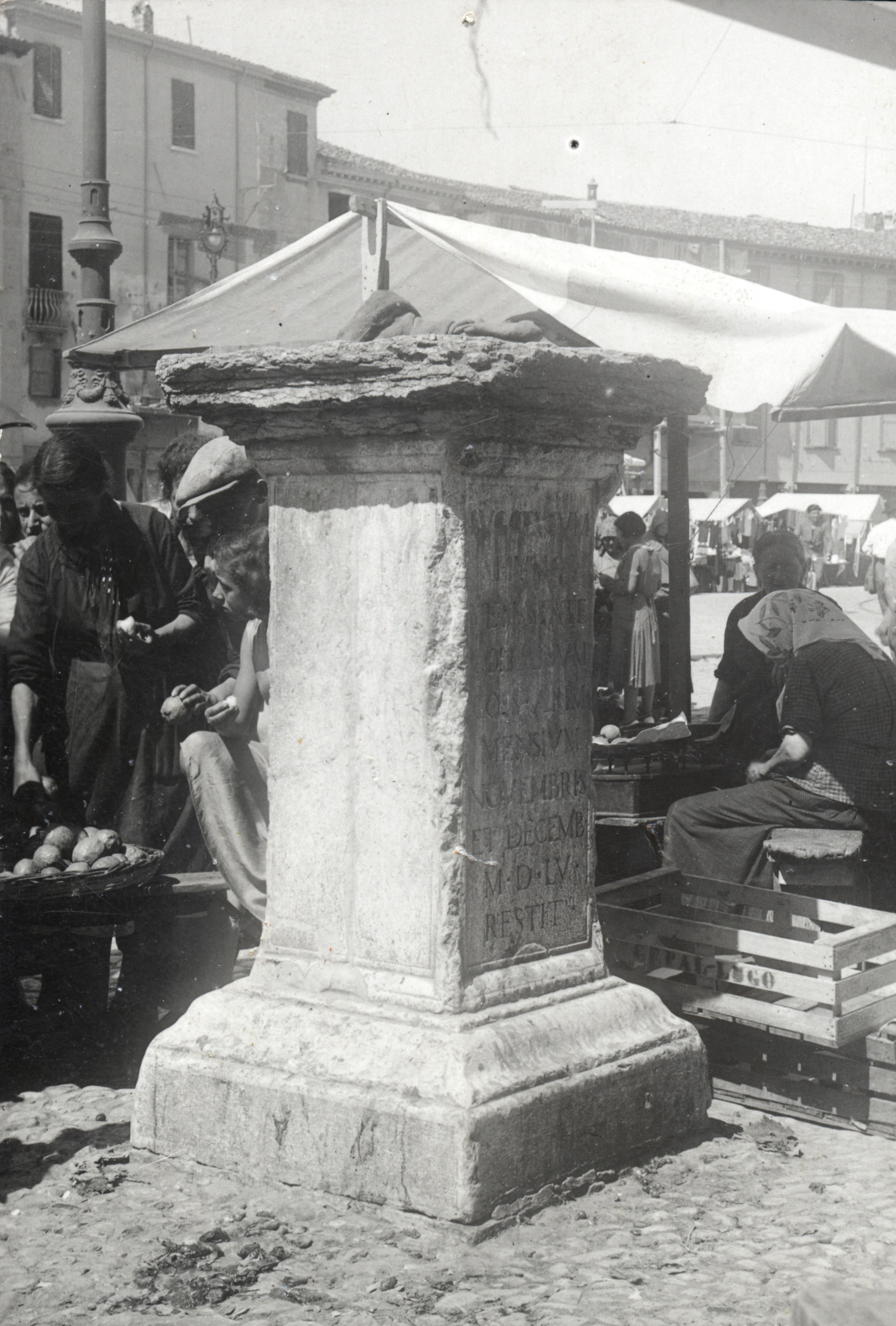 Fig. 1. Cippo e “suggestum” fra le donne del mercato, in una foto del fondo Luigi Pasquini [Archivio fotografico Biblioteca Gambalunga Rimini].